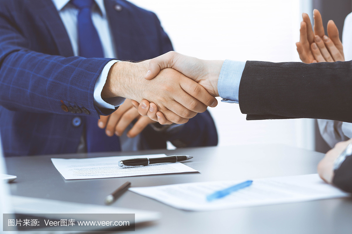 商人們握手,完成一份文件簽名。會議、合同及律師咨詢理念